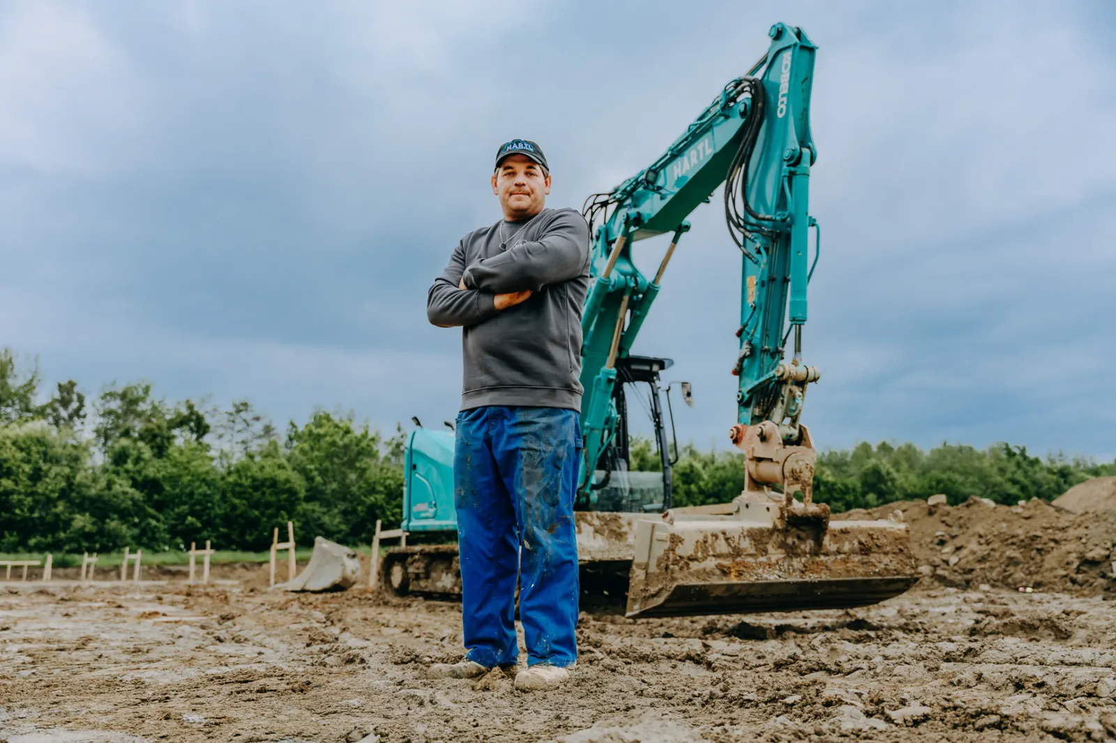 Mitarbeiter von Hartl vor dem Bagger auf der Baustelle